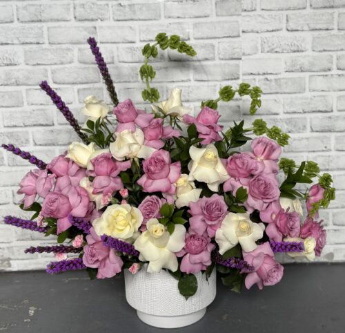 Purple floral arrangement with roses and liatris.