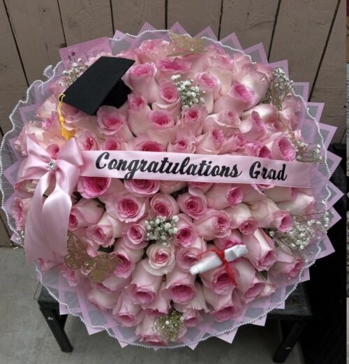 Bouquet of pink roses with a black graduation cap and a pink 'Congratulations Grad' ribbon.