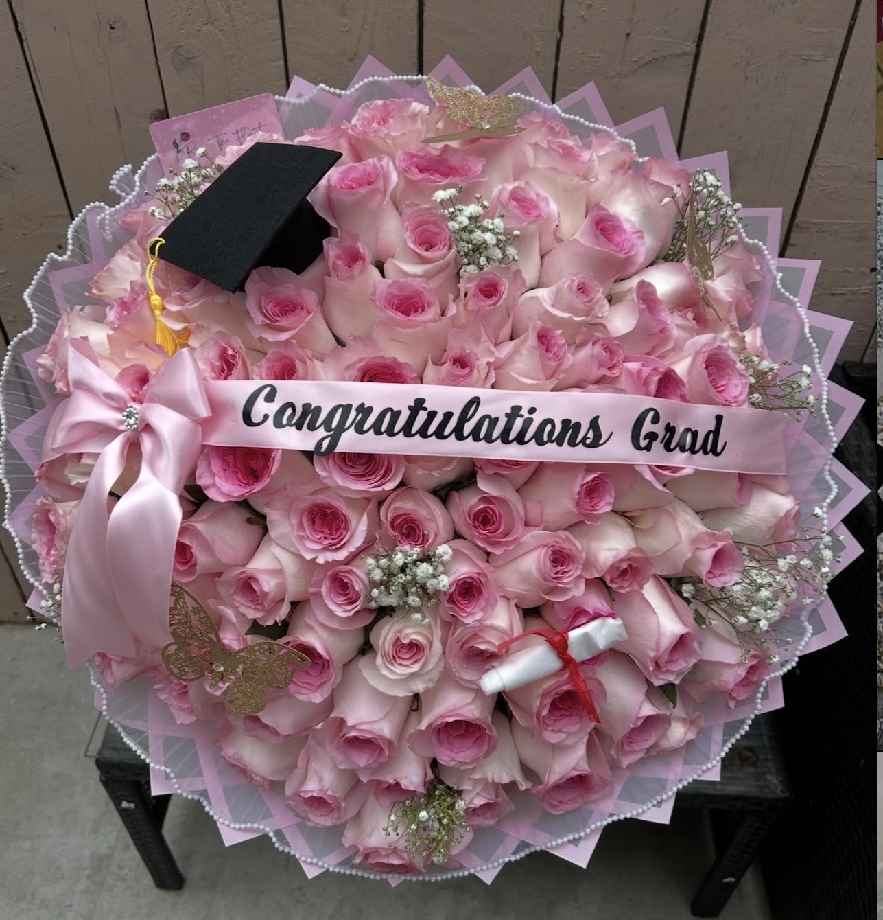Bouquet of pink roses with a black graduation cap and a pink 'Congratulations Grad' ribbon.